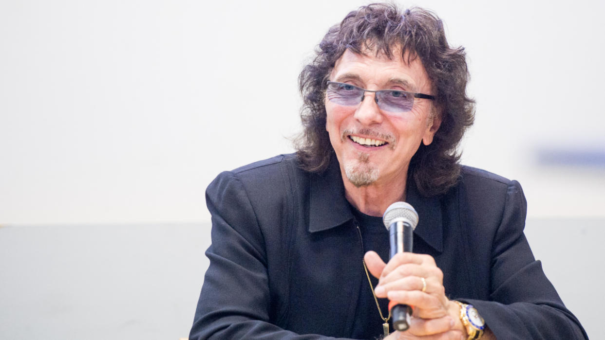  Tony Iommi sat and holding a microphone in 2023. 