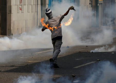 An opposition supporter throws a molotov cocktail during clashes with security forces at a rally against Venezuela's President Nicolas Maduro in Caracas, Venezuela, April 26, 2017. REUTERS/Carlos Garcia Rawlins