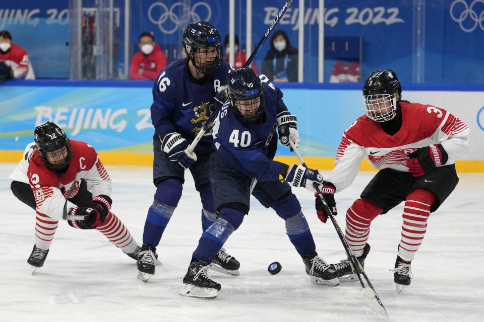 Finland's Noora Tulus (40), and teammate Petra Nieminen (16) battle Japan's Aoi Shiga (3) and teammate Chiho Osawa (12) for the puck during a women's quarterfinal hockey game at the 2022 Winter Olympics, Saturday, Feb. 12, 2022, in Beijing. (AP Photo/Petr David Josek)