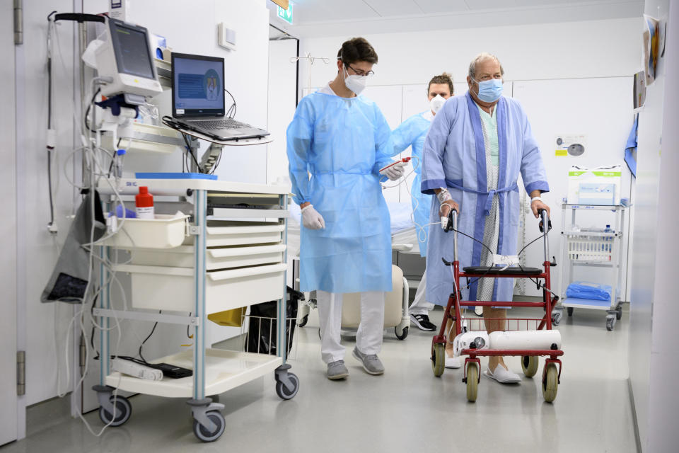 A Swiss army soldier, left, wearing personal protective equipment helps hospital's physiotherapists to mobilize a COVID-19 patient in the intermediate care units of Geneva University Hospitals (HUG), during the coronavirus disease (COVID-19) outbreak, in Geneva, Switzerland, Tuesday, Nov. 17, 2020. Switzerland, as many countries in Europe, requisitioned members of the Civil Protection, the Swiss army and also firefighter to help medical workers in hospitals as cases of Covid-19 patients spike in a second wave of pandemic. (Laurent Gillieron/Keystone via AP)