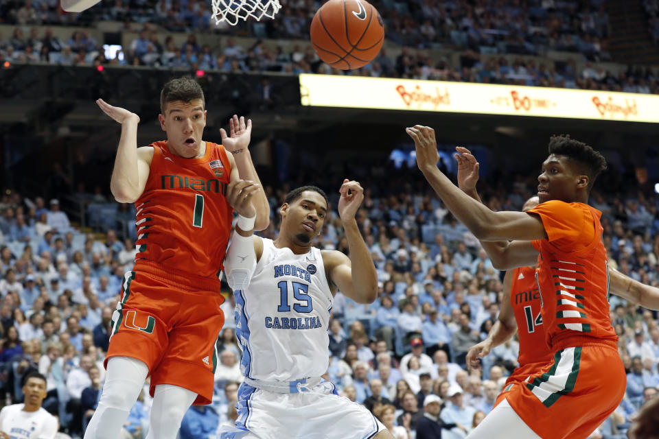 North Carolina forward Garrison Brooks, center, struggles for a rebound with Miami guard Dejan Vasiljevic, left, and forward Anthony Walker, right, during the first half of an NCAA college basketball game in Chapel Hill, N.C., Saturday, Jan. 25, 2020. (AP Photo/Gerry Broome)