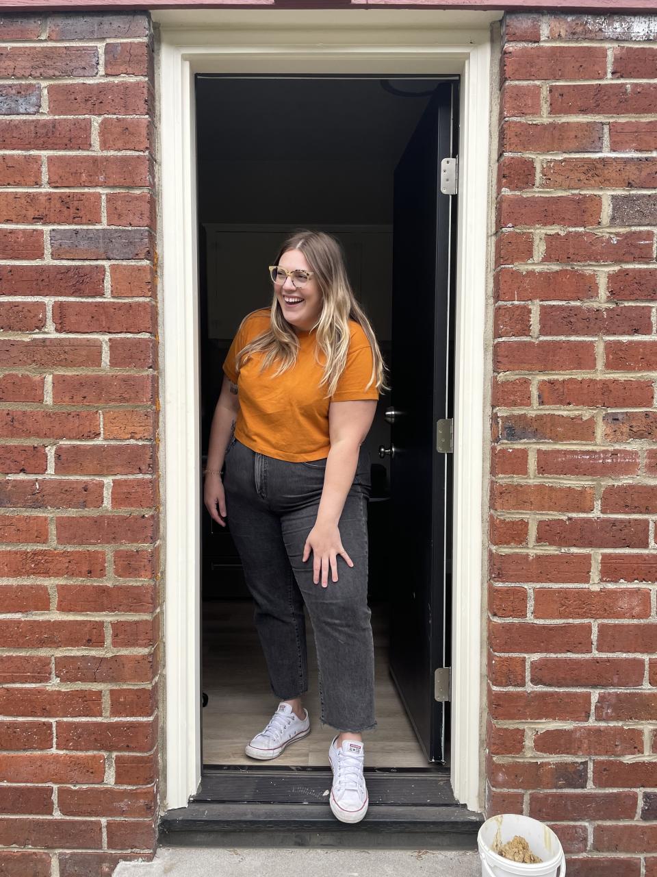 Karli standing in a doorway smiling, dressed in casual attire