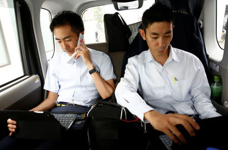 Doctor and founder of Yamato Clinic, Yuu Yasui (R), works whilst on his way to visit a patient with his assistants in Tokyo, Japan, July 4, 2017. REUTERS/Kim Kyung-Hoon