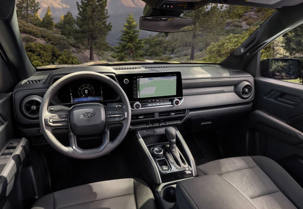 view of colorado trail boss interior from driver's perspective with forrest view through front windshield