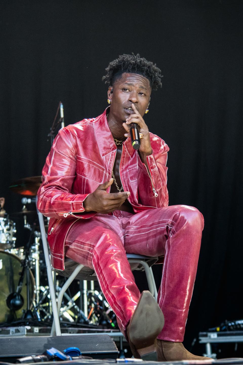 Lucky Daye sits and sings in a red suit