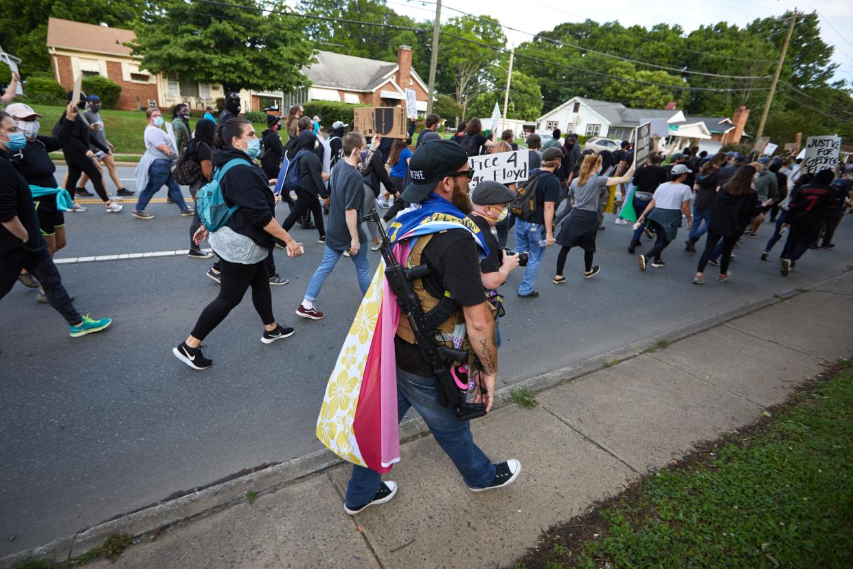 A member of the far-right militia, Boogaloo Bois, walks next to protestors demonstrating outside Charlotte Mecklenburg Police Department Metro Division 2 just outside of downtown Charlotte, North Carolina, on May 29, 2020. - The protest was sparked by protests in Minneapolis, over the death of George Floyd, a black man who died after a white policeman kneeled on his neck for several minutes. In Charlotte, CMPD Metro Division 2 was home to CMPD officer, Wende Kerl, who shot and killed Danquirs Franklin outside of a Burger King on March 25, 2019. CMPD found that officer Kerl operated in the constraints of the law but later a citizen review board would find that the officers actions were not justified. No charges were ever brought. (Photo by Logan Cyrus / AFP) (Photo by LOGAN CYRUS/AFP via Getty Images)