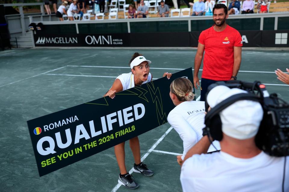 Romania's Jaqueline Cristian holds up a sign after winning as she celebrates victory with doubles partner Ana Bogdan.