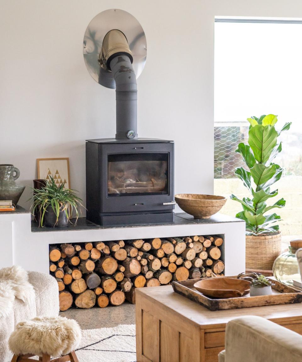 A log burning stove in a living room with built in log storage underneath
