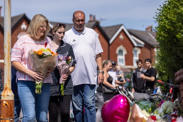 People laying flowers by side of road