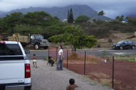 Josephine Fraser, 22, born and raised in Lahaina, goes on a walk with her dog, Keao, and sons Ireh Dias, 3, front, and Zyon Dias, 18 months, outside their small home at Ke Ao Maluhia at the Maui Lani housing development, spearheaded by the Council for Native Hawaiian Advancement, Wednesday, July 10, 2024, in Kahului, Hawaii. The family has moved 10 times over the past 11 months after being displaced by the 2023 wildfire and are the first to move into the modular home community being built for those affected. (AP Photo/Lindsey Wasson)