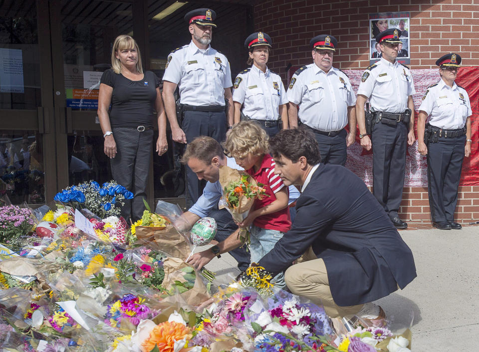 <p>Prime Minister Justin Trudeau, accompanied by his four-year-old son Hadrien and Fredericton MP Matt DeCourcey, left, places flowers outside the police station in Fredericton on Sunday, Aug. 12, 2018. Two city police officers were among four people who died in a shooting in a residential area on the city’s north side. (Photo from The Canadian Press/Andrew Vaughan </p>