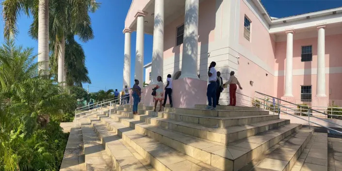 A pink courthouse with people in front of it.