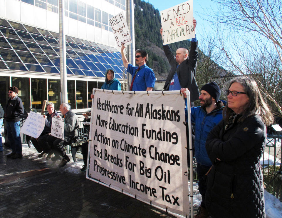 FILE - In this Feb. 27, 2019 file photo, protesters attend a rally at the Capitol in Juneau, Alaska, to show opposition to budget cuts proposed by Gov. Mike Dunleavy. For decades, Alaska has had an uneasy reliance on oil, building budgets around its volatile boom-or-bust nature. When times were rough, prices always seemed to rebound, forestalling a day of reckoning some believe may finally have come. The situation has politicians weighing changes to the annual dividend paid to residents from earnings of the state's oil-wealth fund, the Alaska Permanent Fund. (AP Photo/Becky Bohrer, File)
