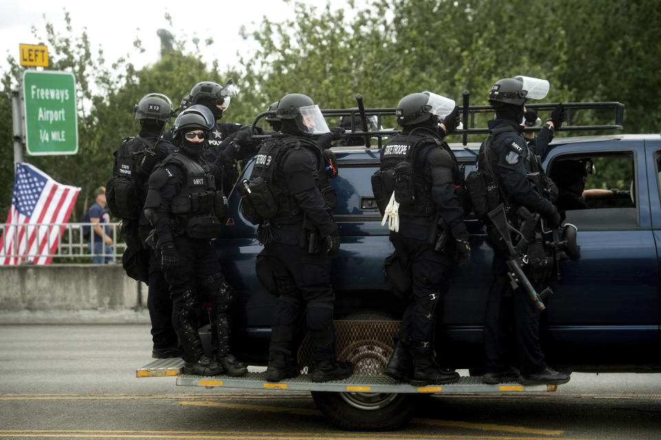 Police officers ride on the side of a vehicle as right-wing demonstrators and counter-protesters gather in Portland, Ore., for an "End Domestic Terrorism" rally on Saturday, Aug. 17, 2019. Right-wing groups and counterprotesters gathered in downtown Portland and authorities set up concrete barriers and closed streets in an effort to contain the two groups.(AP Photo/Noah Berger)
