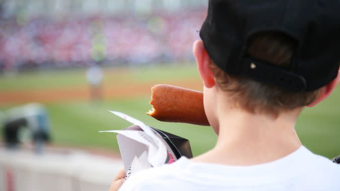 Young boy eating a corndog at a major league baseball game.