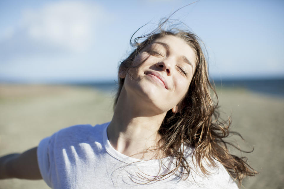 Woman smiling with her hair blowing in the wind looking calm and relaxed