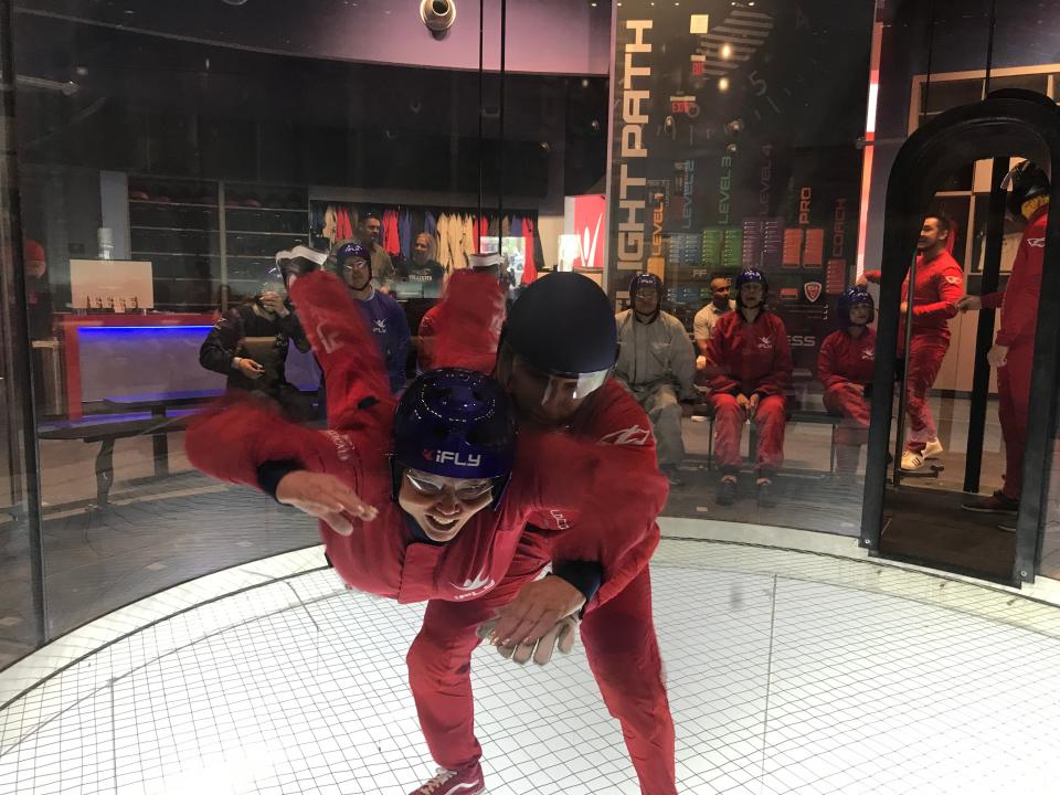 A flight instructor helps first-time flyer Karen Cowell hold steady inside the wind tunnel at iFly indoor skydiving.