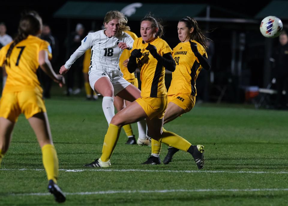 Michigan State's Justina Gaynor (18) blasts the ball between Milwaukee's Lexi Blaser (27) and Brooke Parnello (29) Friday, Nov. 11, 2022. Gaynor scored a goal in the 1st round of the NCAA Championships which Michigan State won 3-2.