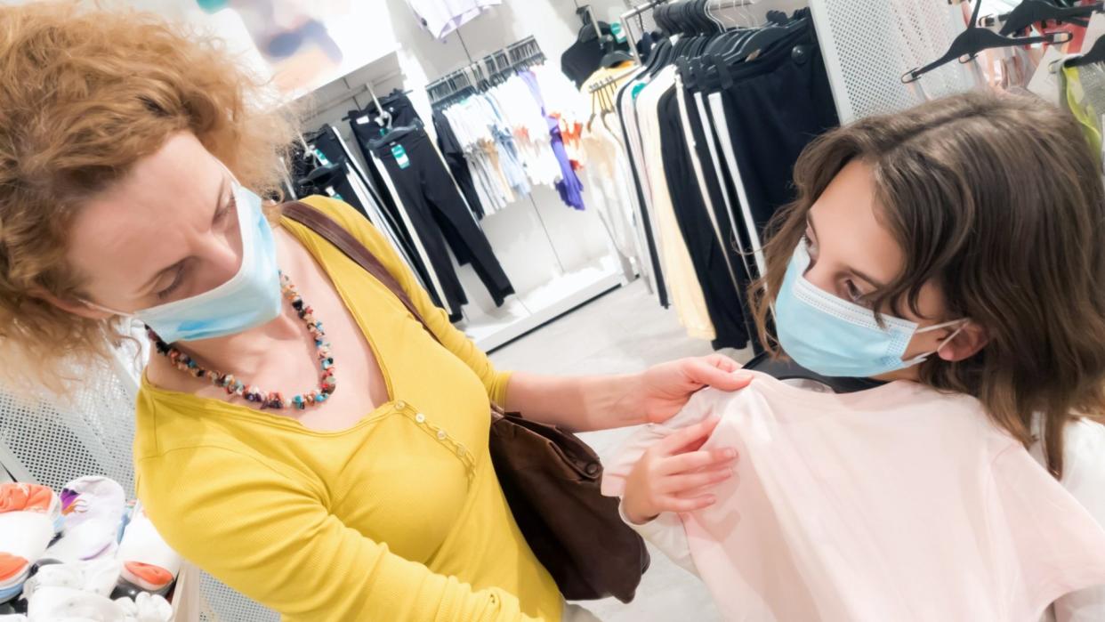 Mother and daughter in shopping mall with protective medical masks for protection of virus in time of epidemic and pandemic.