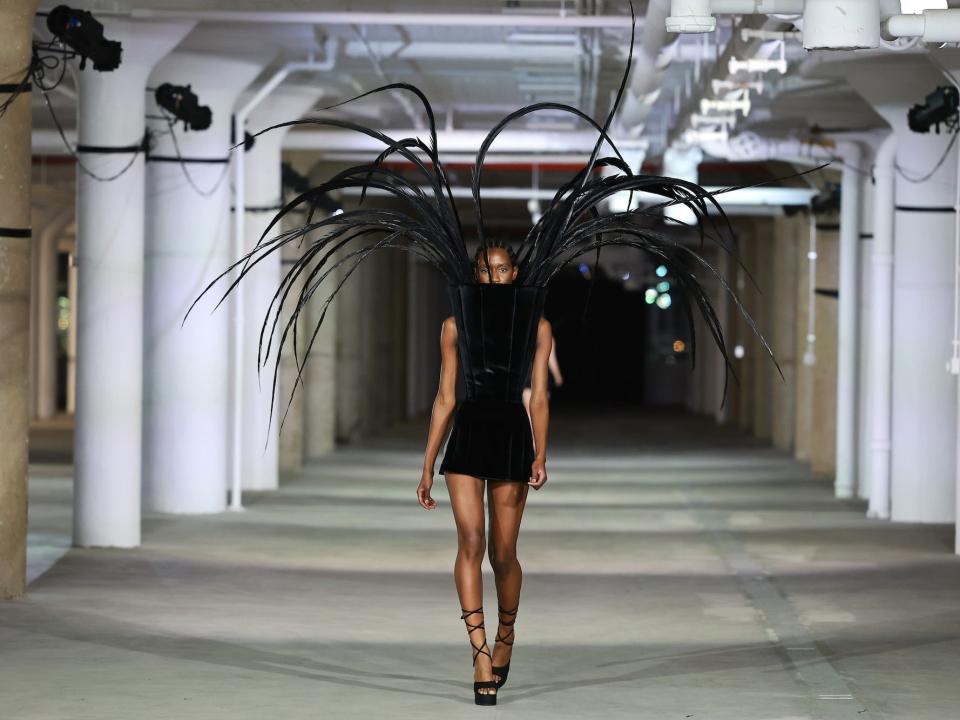 A model wears a feathered Christian Cowan look on the Fall/Winter 2023 runway.