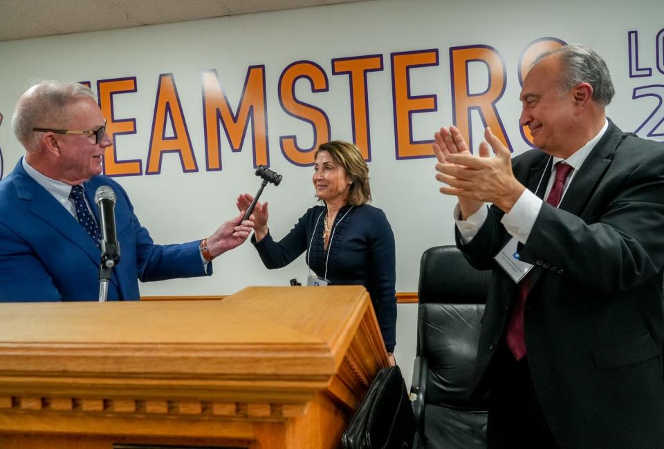 Rep. Joseph McNamara, outgoing state chairman of the Rhode Island Democratic Party, hands Elizabeth Beretta-Perik the gavel after she was elected as the new party chair. At right is state Rep. Arthur Corvese.