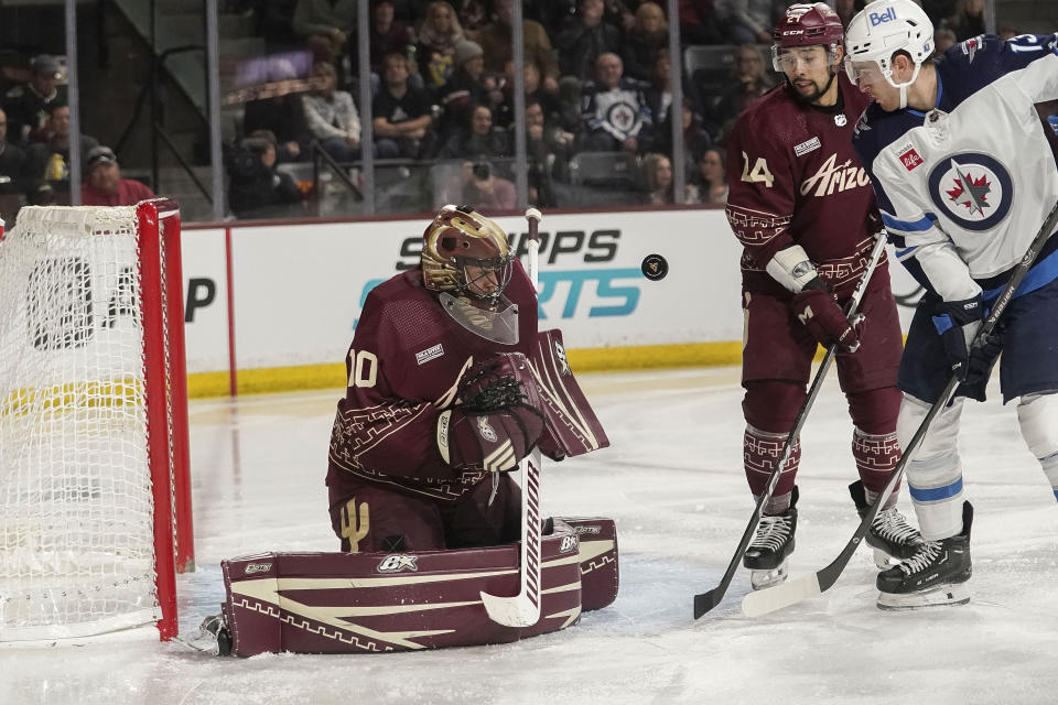 Arizona Coyotes goalie Karel Vejmelka, left, blocks a shot by Winnipeg Jets' Gabriel Vilardi (13) as Coyotes' Matt Dumba (24) watches during the first period of an NHL hockey game Sunday, Jan. 7, 2024, in Tempe, Ariz. (AP Photo/Darryl Webb)