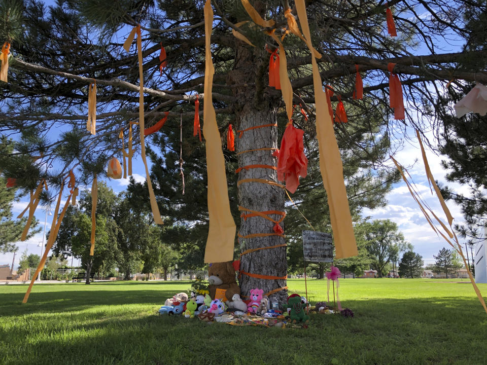 A makeshift memorial for the dozens of Indigenous children who died more than a century ago while attending a boarding school that was once located nearby is growing under a tree at a public park in Albuquerque, N.M., on Thursday, July 1, 2021. Indigenous activists are concerned that a plaque that noted the site of the burial ground was removed in recent days. (AP Photo/Susan Montoya Bryan)