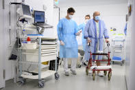 A Swiss army soldier, left, wearing personal protective equipment helps hospital's physiotherapists to mobilize a COVID-19 patient in the intermediate care units of Geneva University Hospitals (HUG), during the coronavirus disease (COVID-19) outbreak, in Geneva, Switzerland, Tuesday, Nov. 17, 2020. Switzerland, as many countries in Europe, requisitioned members of the Civil Protection, the Swiss army and also firefighter to help medical workers in hospitals as cases of Covid-19 patients spike in a second wave of pandemic. (Laurent Gillieron/Keystone via AP)