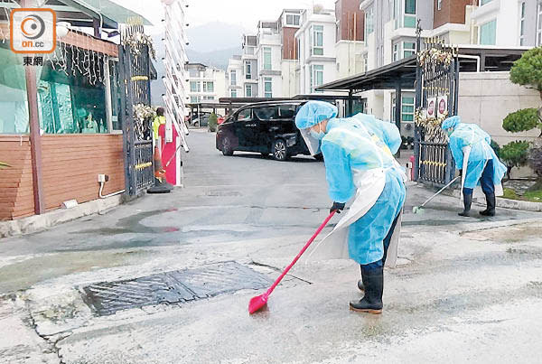 食環署職員在謝的寓所門外消毒、洗地。