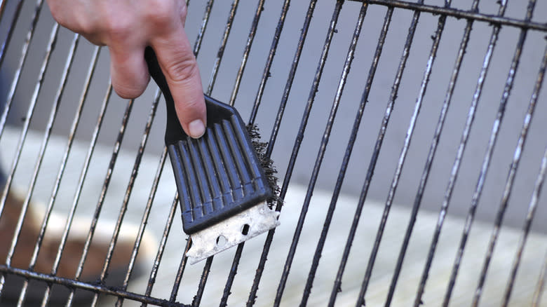 hand scrubbing a grill with a brush