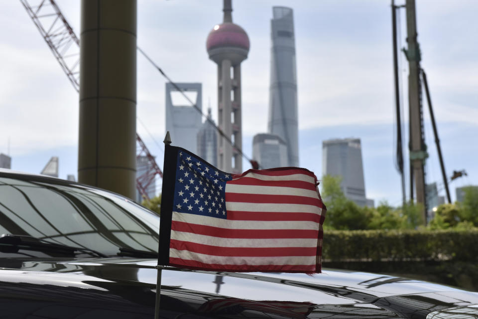 A U.S. flag flies on a U.S. consulate car, with the backdrop of buildings in the Lujiazui financial district, outside a hotel where U.S. trade negotiators are staying, in Shanghai Wednesday, July 31, 2019. (Greg Baker/Pool Photo via AP)