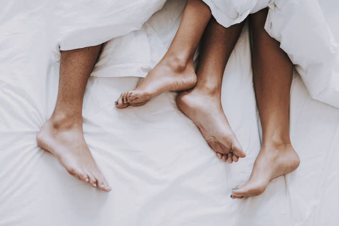 A couple's feet peak out of bed covers