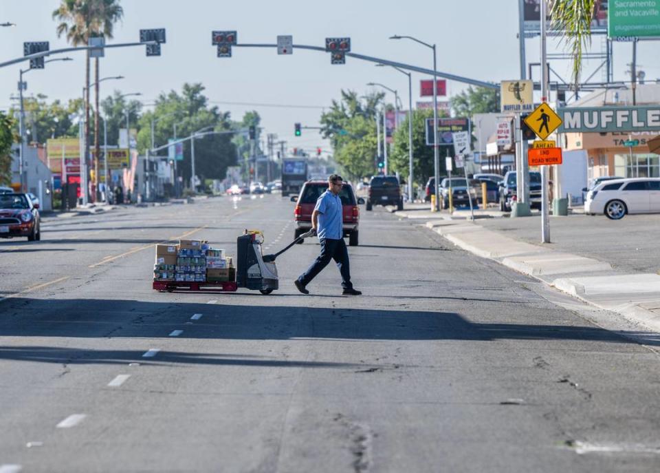 A delivery man crosses Franklin Blvd. on Thursday, Sept. 7, 2023. The Franklin Boulevard Complete Street project, set to begin construction in 2024, plans to add protected bike lanes, wider sidewalks, better street lighting and more shade trees to in the North City Farms neighborhood of Sacramento.