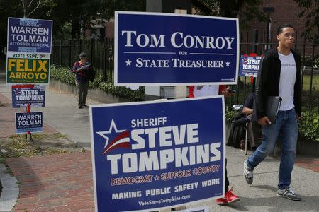 Pedestrians walk past signs with names of candidates outside a polling station on primary election day in Boston, Massachusetts September 9, 2014. REUTERS/Brian Snyder