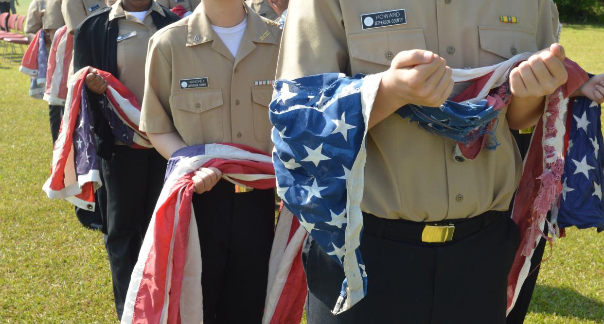 Jefferson County High School NJROTC cadets carry tattered and worn United States Flags to the flames for retirement.