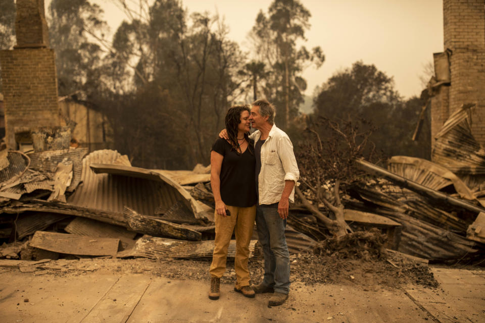 Business owner Sally Anne Wilson (left) stands in front of her destroyed shop with her partner Christopher Lee in Cobargo.