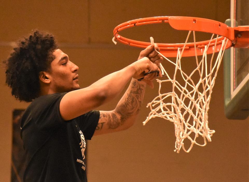 Herkimer College General Anthony Douglas Jr cuts a piece of the net following the NJCAA's Region III championship game Sunday.