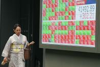 A person in traditional Japanese "kimono" walks in front of an electronic stock board showing Japan's Nikkei index at a securities firm Tuesday, July 16, 2024, in Tokyo. (AP Photo/Eugene Hoshiko)