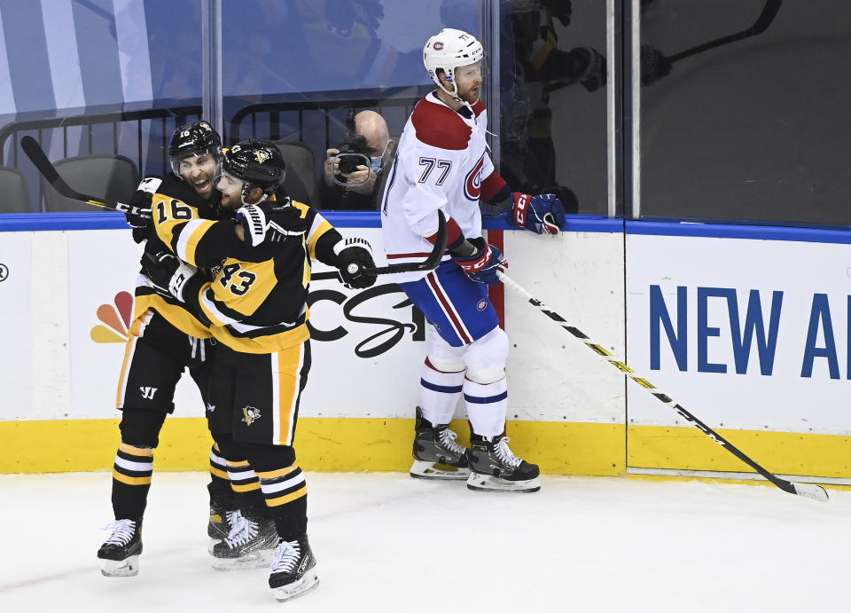 Pittsburgh Penguins left wing Jason Zucker (16) celebrates his goal with teammate Conor Sheary (43) as Montreal Canadiens defenseman Brett Kulak (77) skate by during the third period of an NHL hockey playoff game Monday, Aug. 3, 2020 in Toronto. (Nathan Denette/The Canadian Press via AP)