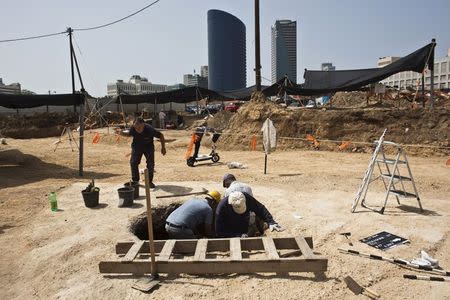 Workers for the Israel Antiquities Authority (IAA) stand in a pit at an archaeological dig in a future construction site in Tel Aviv, where fragments of ancient basins were unearthed, March 29, 2015. REUTERS/Nir Elias