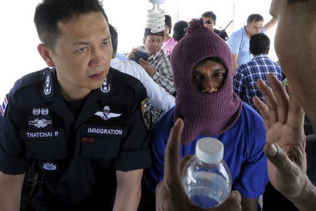 Police Major General Thatchai Pitaneelaboot (L) listens as a Rohingya trafficking victim leads a police unit to a camp where he was detained in Satun, southern Thailand in this March 27, 2014 file photo. REUTERS/Andrew RC Marshall/Files
