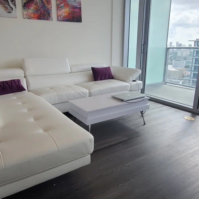 Modern living room with a white sectional sofa, matching ottoman and a sleek coffee table