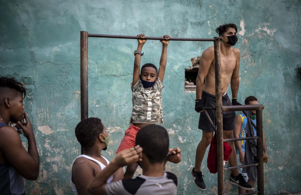Youths wearing masks against the spread of the new coronavirus exercises at a street gym in Havana, Cuba, Monday, Dec. 21, 2020. (AP Photo/Ramon Espinosa)