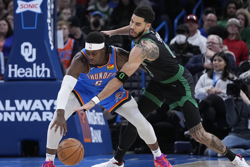 Boston Celtics forward Jayson Tatum, right, tries to knock the ball away from Oklahoma City Thunder guard Luguentz Dort (5) in the first half of an NBA basketball game Tuesday, Jan. 3, 2023, in Oklahoma City. (AP Photo/Sue Ogrocki)