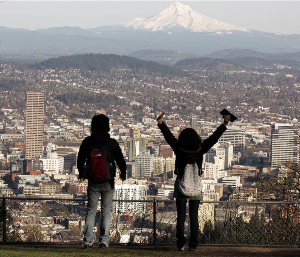 FILE - In this file photo from Feb. 26, 2008, a young couple enjoys the view of Mount Hood looming over downtown on a spring-like day in Portland, Ore. A famous quip by Fred Armisen on the television show "Portlandia" led Portland State University researchers to investigate the reality behind the comment. The quirky IFC network series pokes fun at the Oregon city's many eccentricities. (AP Photo/Don Ryan, File)