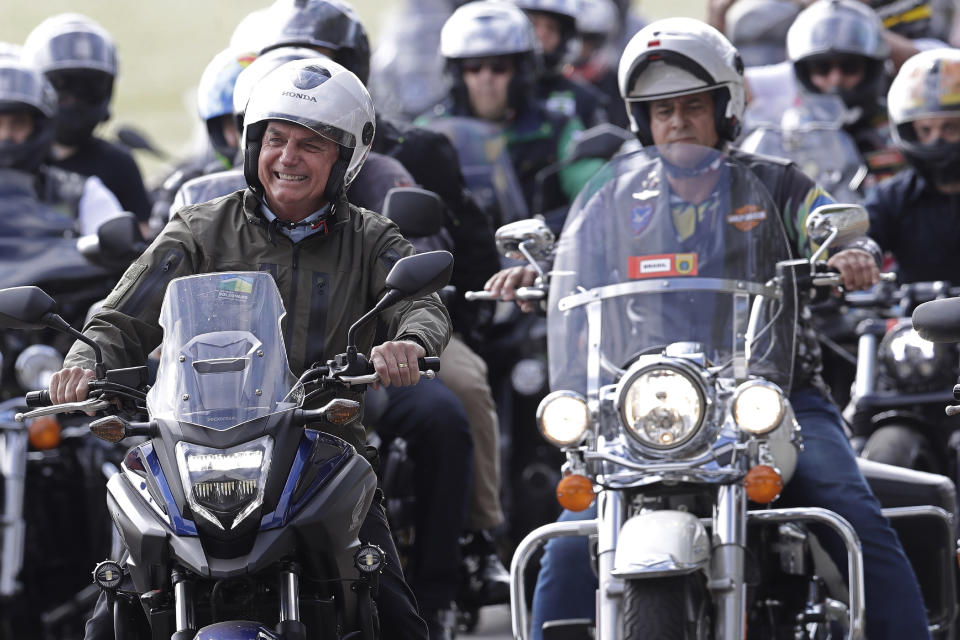 FILE - In this May 9, 2021 file photo, Brazil's President Jair Bolsoanro, left, takes a motorcycle tour with supporters representing the moto clubs in honor of Mother's Day, in Brasilia, Brazil. Bolsonaro has waged a 15-month campaign to downplay the virus’s seriousness and keep the economy humming, dismissing the pandemic early on as “a little flu” and has scorned masks. (AP Photo/Eraldo Peres, File)