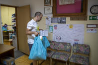 Igor Loparic prepares packages of aid for people in need for help in Pula, Croatia, Tuesday, May 26, 2020. As local businesses suffered under the coronavirus lockdown, even once well-off families have found themselves struggling and many have turned to the local "Our Dream Their Smile" group for help with food, other necessities or legal advice.(AP Photo/Darko Bandic)