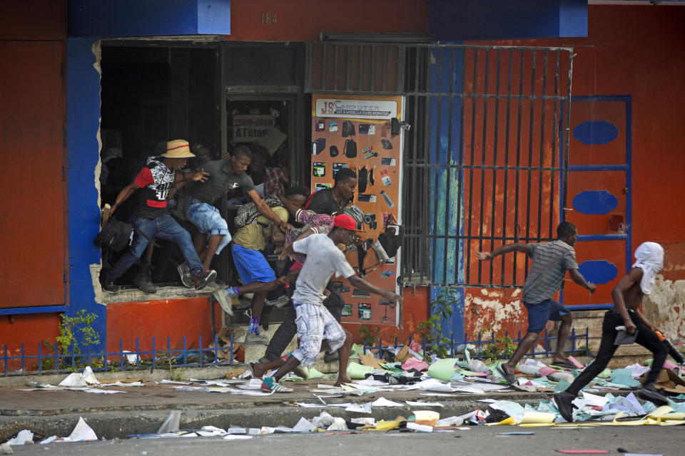 Looters run away from a store as national police arrive during a protest demanding the resignation of Haitian President Jovenel Moise in Port-au-Prince, Haiti, Feb. 12, 2019. The image was part of a series of photographs by Associated Press photographers which was named a finalist for the 2020 Pulitzer Prize for Breaking News Photography. (AP Photo/Dieu Nalio Chery)