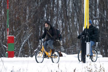 Two migrants on bicycles cross the border between Norway and Russia in Storskog near Kirkenes in Northern Norway, November 16, 2015. REUTERS/Cornelius Poppe/NTB Scanpix/File Photo