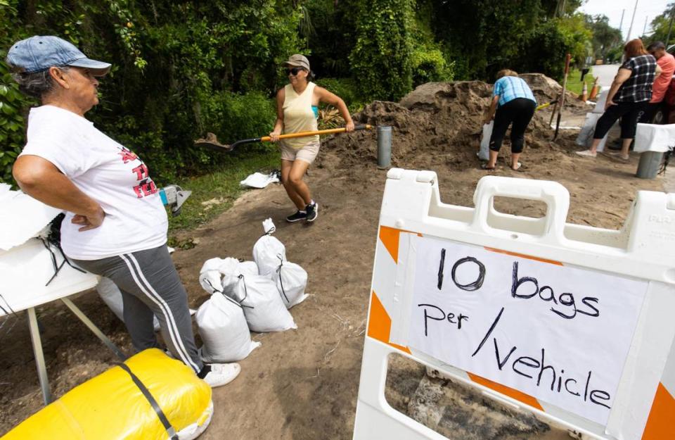 Edna Ramirez carries a shovel full sand to a bagging station as people were doing the same at the Dunnellon Public Works site on Bostick Street Tuesday morning, August 29, 2023. On Monday, Dunnellon had filled 1500 bags while on Tuesday that had given out 2500 bags by noon. [Doug Engle/Ocala Star Banner]2023